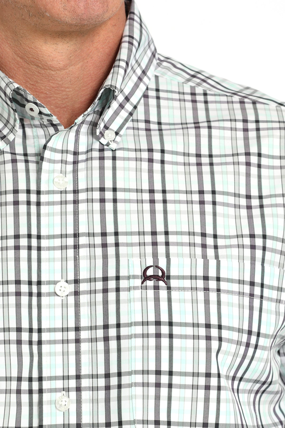 Close-up of a checkered shirt with a brand logo on a white background