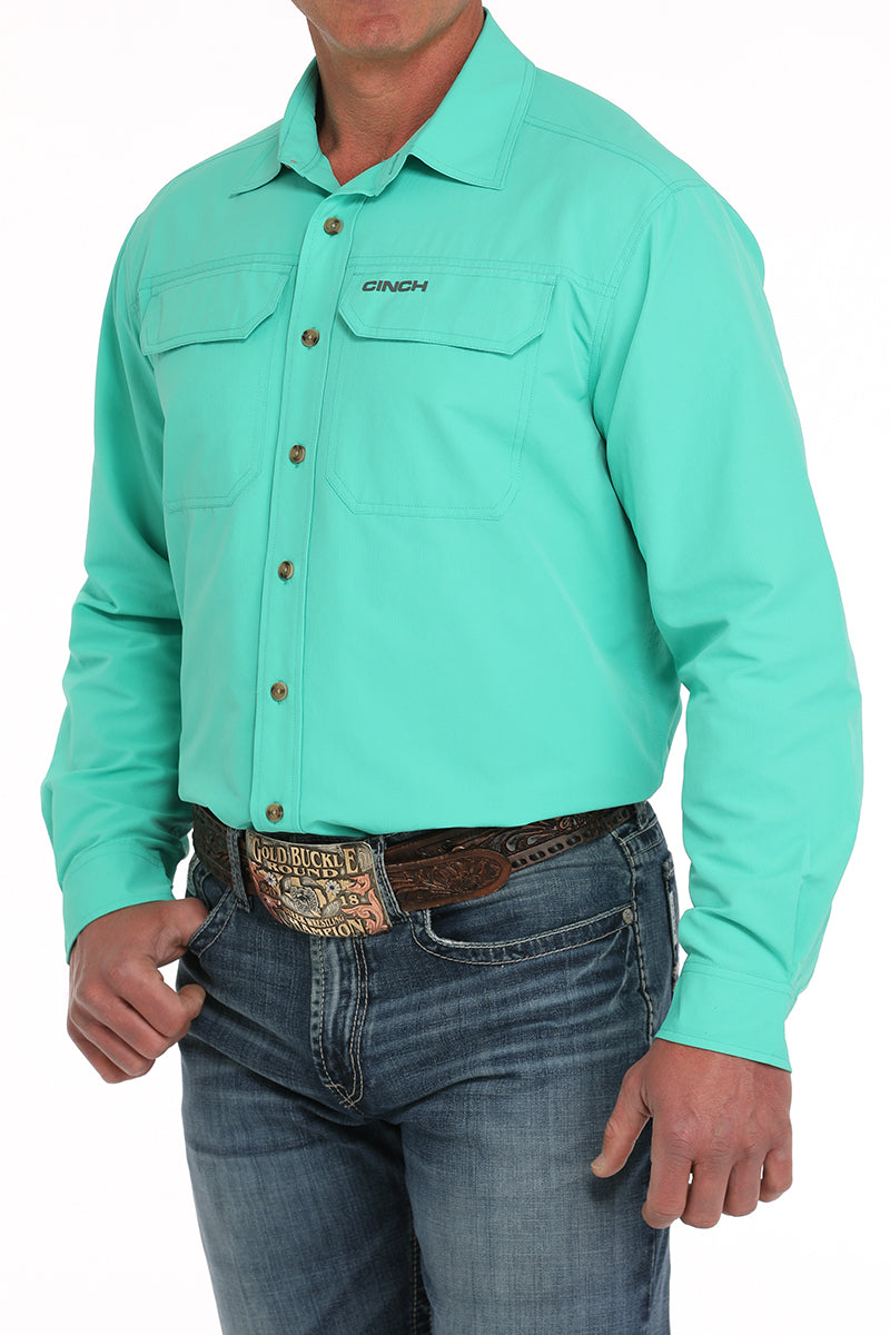 Person wearing a turquoise shirt with a belt and jeans on a white background