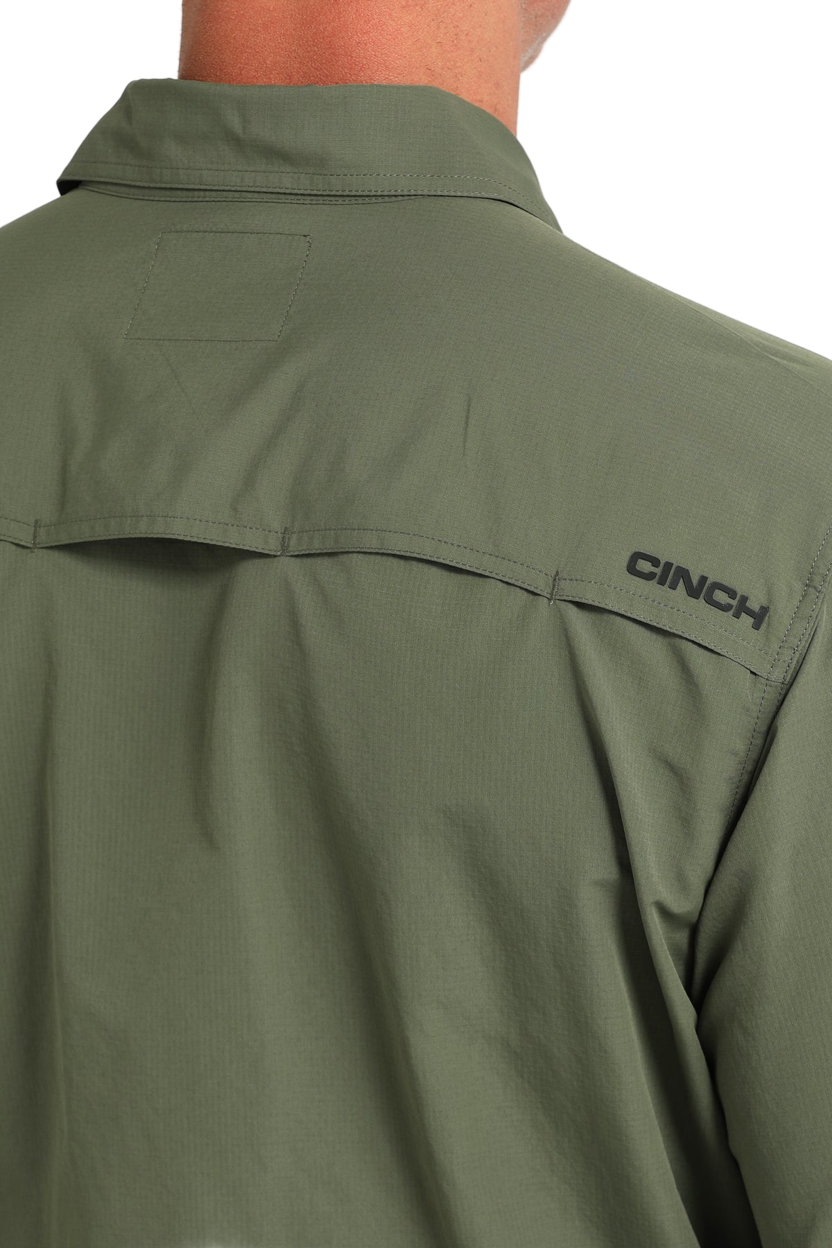 Back view of a man wearing a green 'Cinch' long sleeve shirt with a collar on a transparent background