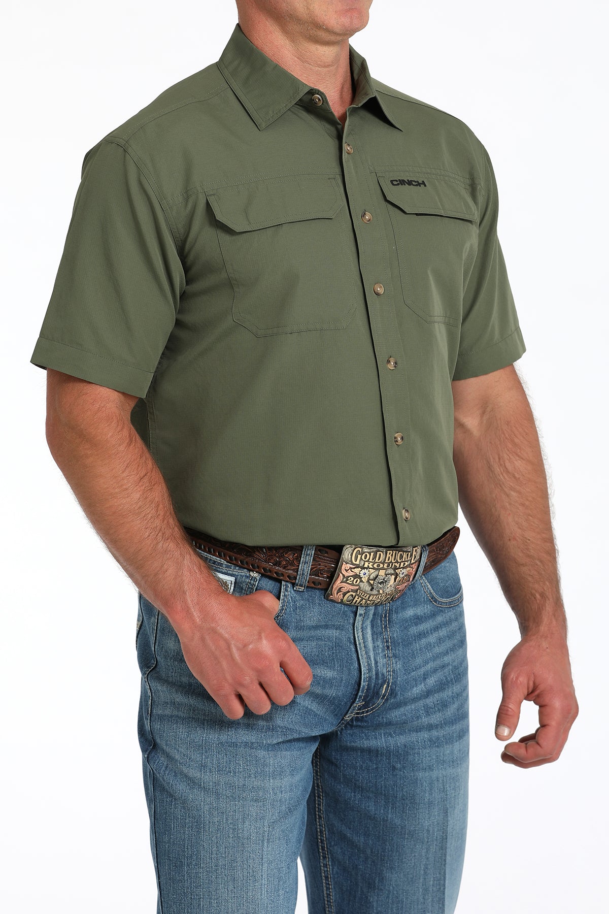 Man wearing a green short-sleeve shirt with a belt and jeans on a white background