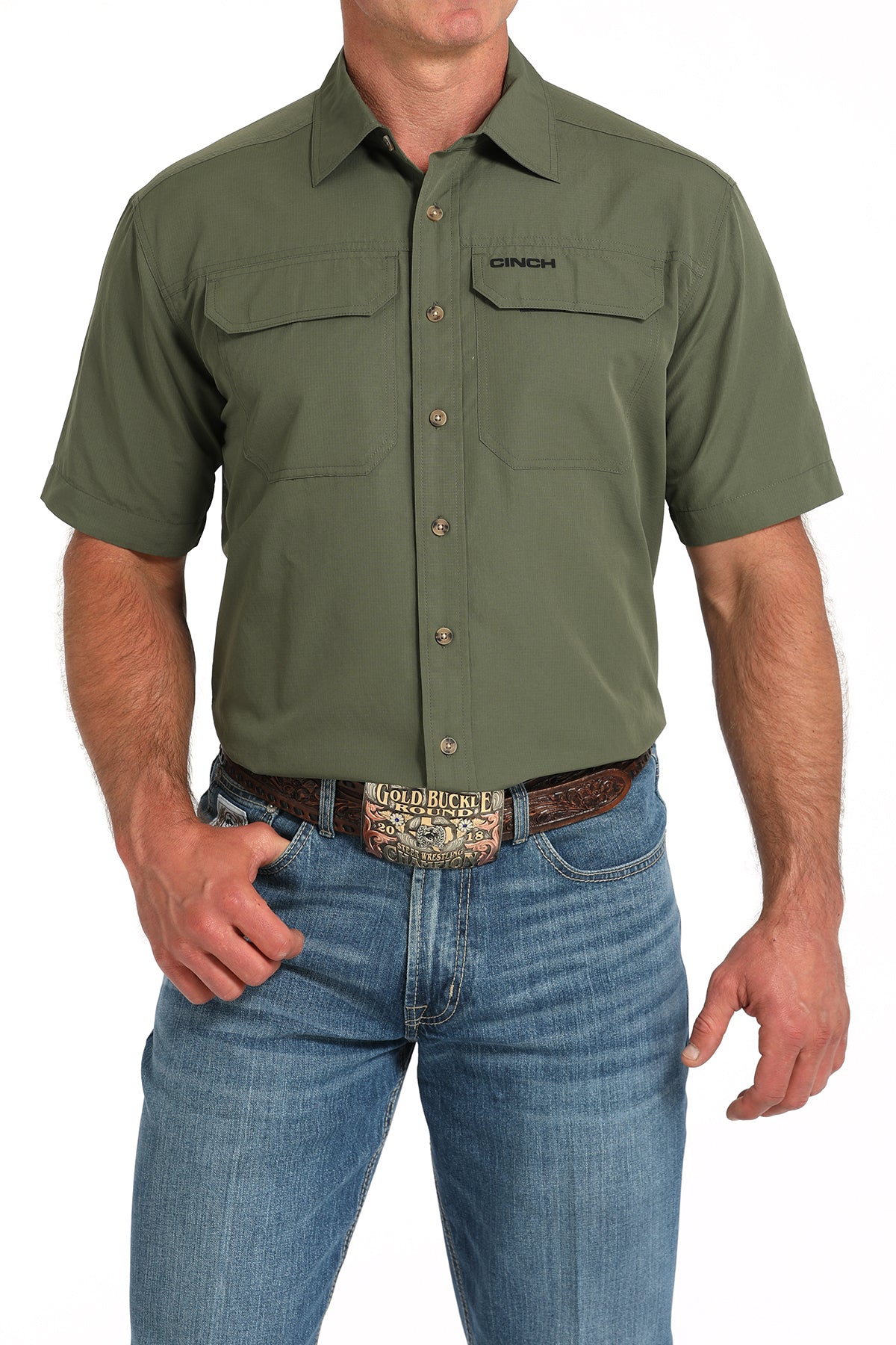 Man wearing a green short-sleeve shirt with a belt and jeans on a white background