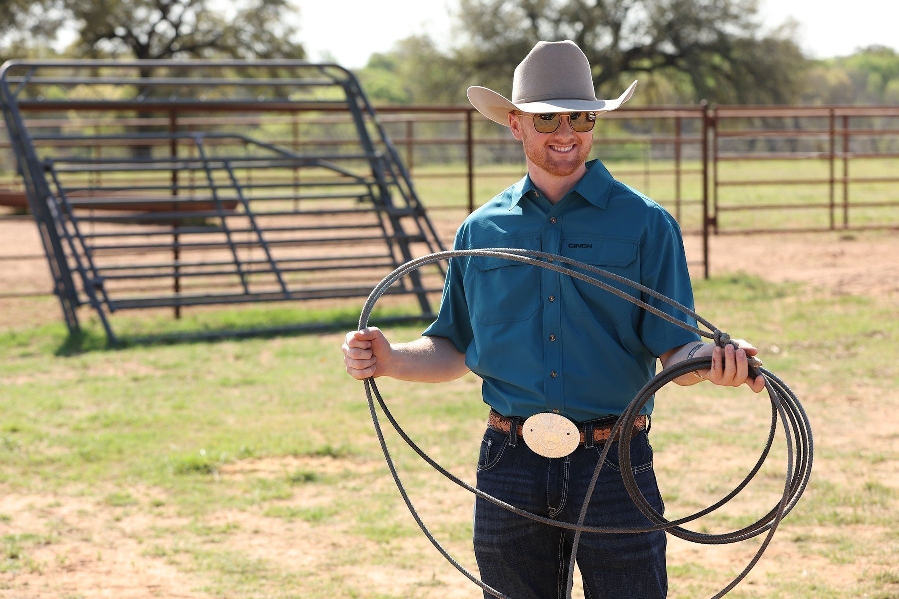 Go West Supply Men's short-sleeve teal poly-spandex Arenaflex shirt with embroidered logo and pearl buttons.