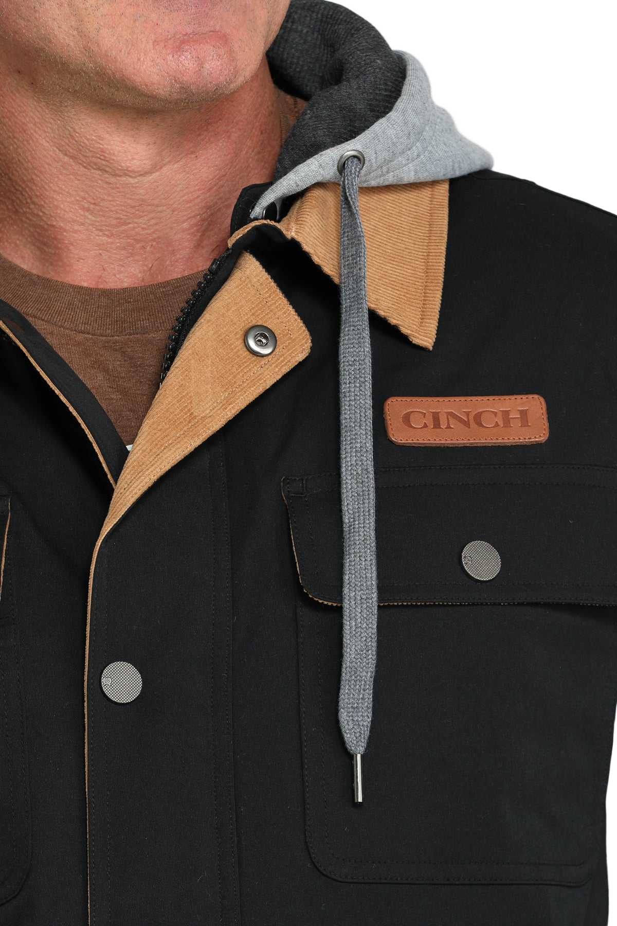 Close-up of a man wearing a black jacket with a tan collar and attached gray hood