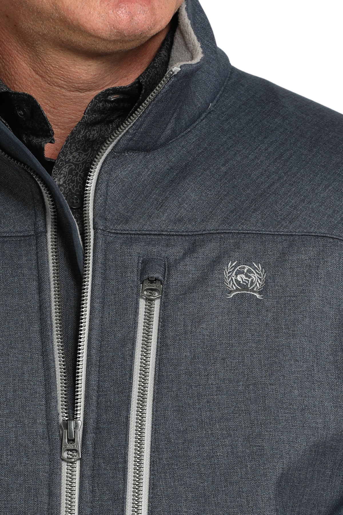 Close-up of a man wearing a blue zip-front jacket