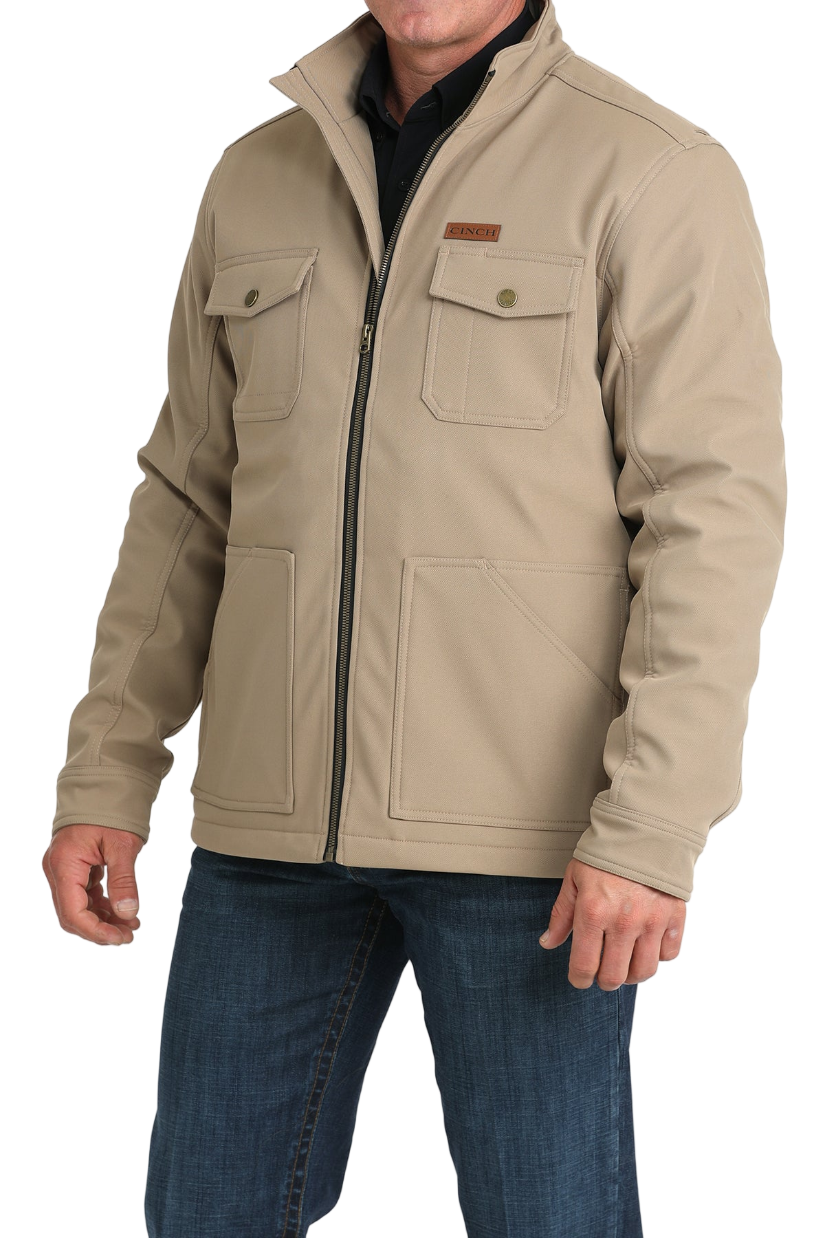 Man wearing a tan zip-front jacket with buttoned chest pockets, paired with dark jeans