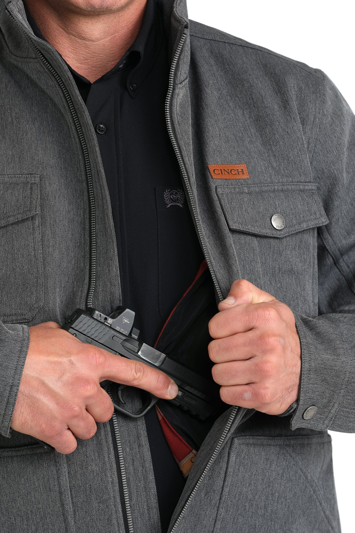 Man wearing a gray jacket, shown partially unzipped to reveal an interior concealed-carry pocket