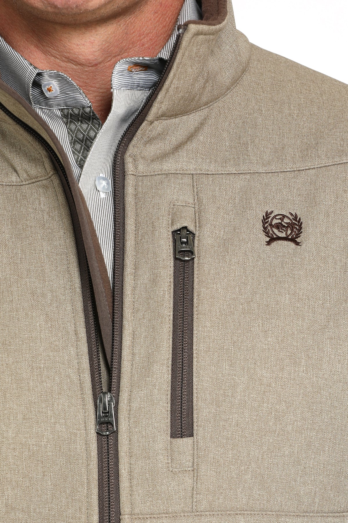Close-up of a man wearing a khaki jacket with contrasting zipper color