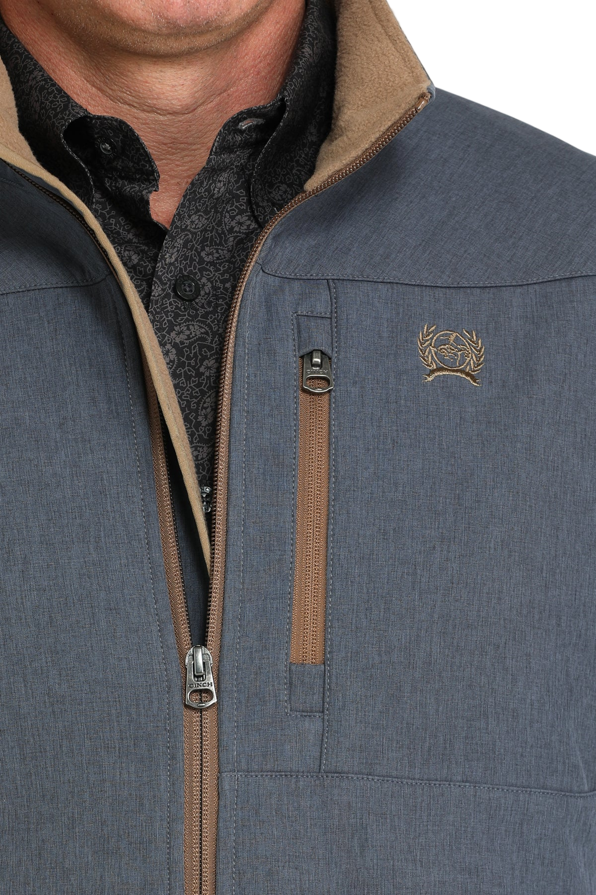 Close-up of a man wearing a blue softshell jacket with tan accents