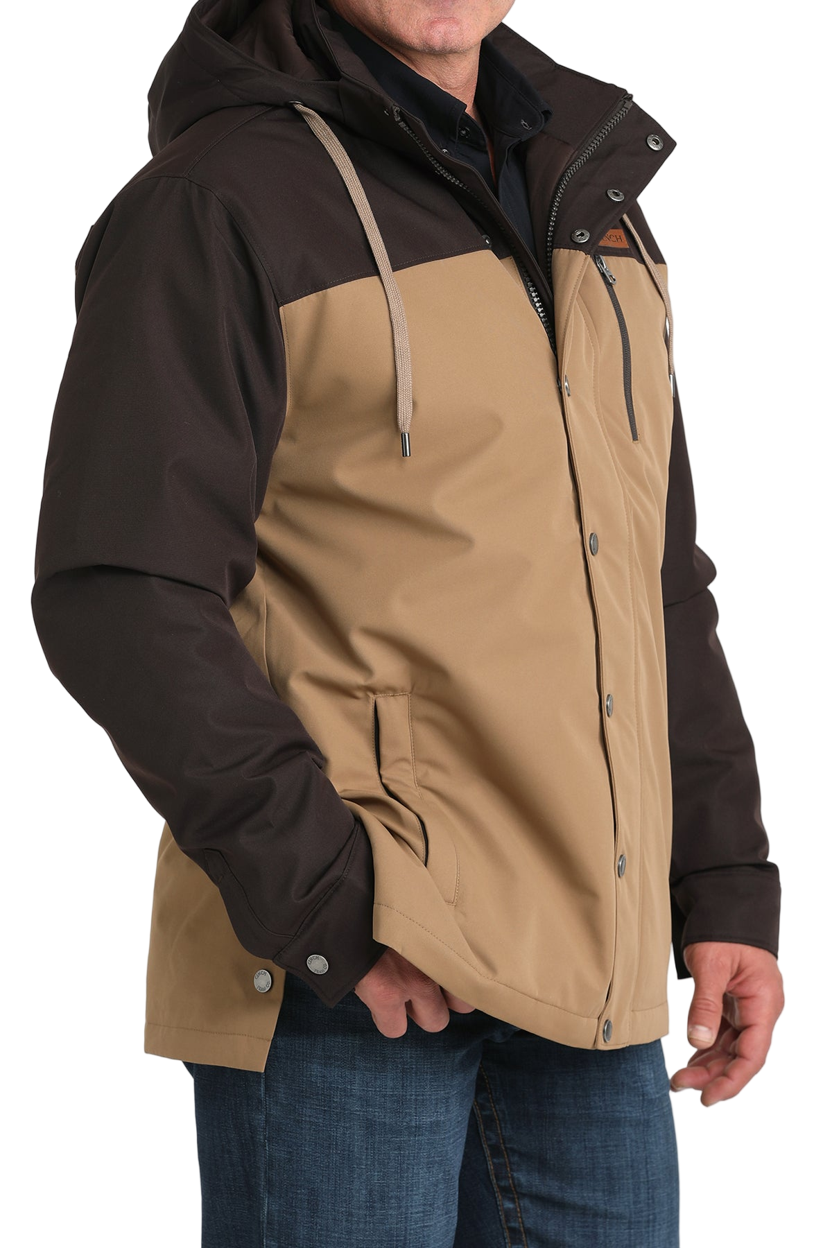 Man wearing a two-tone brown hooded jacket paired with blue jeans