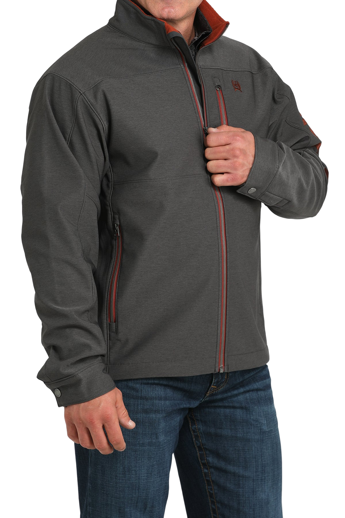 Man wearing a charcoal gray softshell jacket with bold red accents, paired with blue jeans