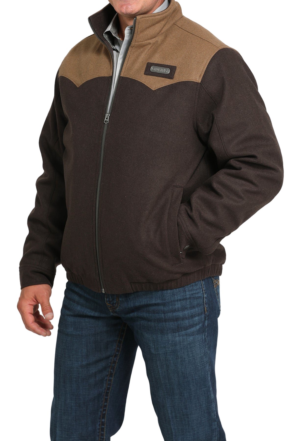 Man wearing a brown zip-up jacket with a lighter brown yoke detail, paired with blue jeans