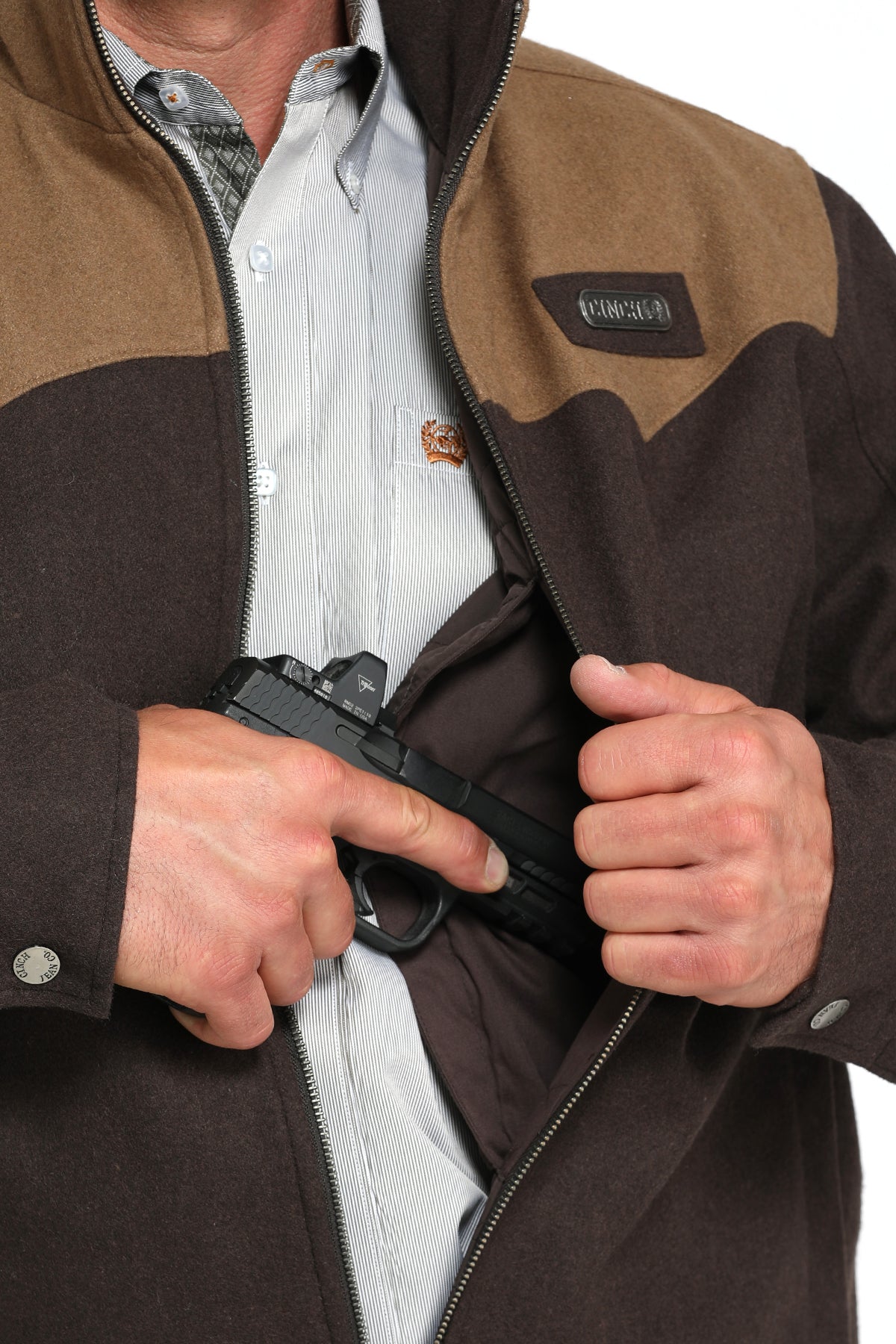 Close-up of a man wearing a two-toned brown jacket showing a partial firearm going into the concealed carry pocket