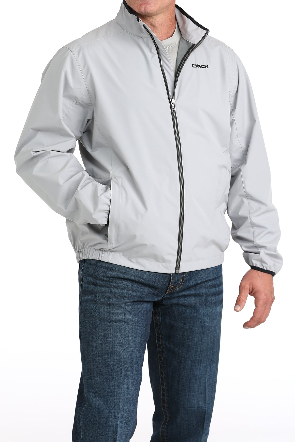 Person wearing a light gray jacket with a brand logo on a white background