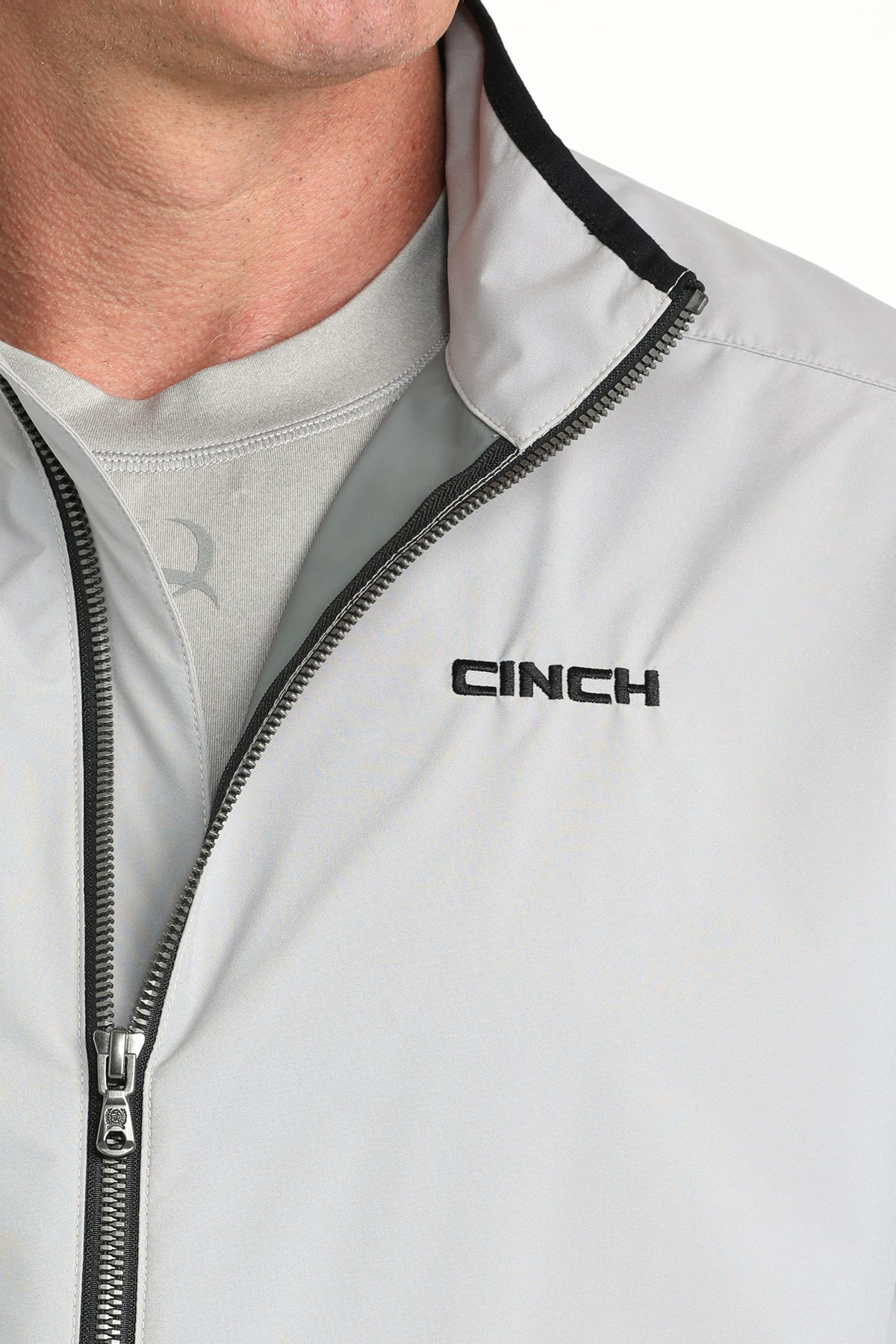Close-up of a light gray jacket with black zipper and 'CINCH' logo.