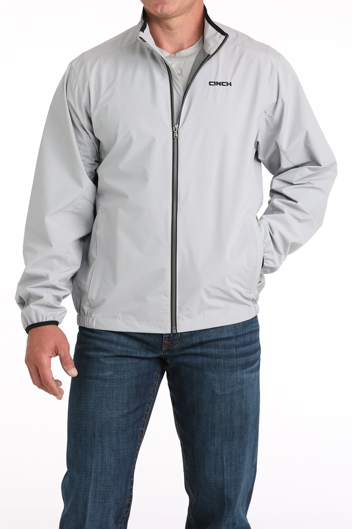 Man wearing a light gray jacket with a brand logo on a white background