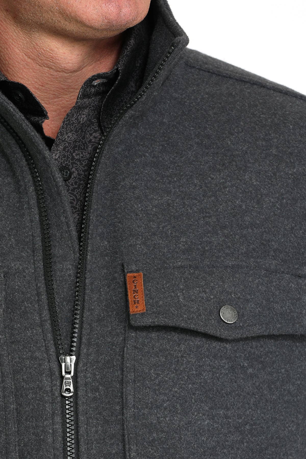 Close-up of a man wearing a gray jacket with a zipper and a chest pocket