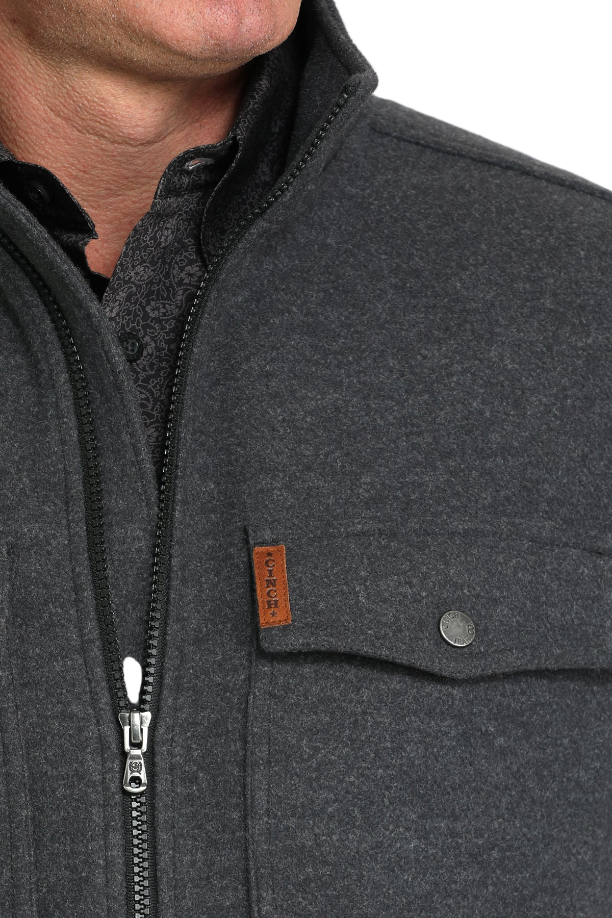 Close-up of a man wearing a dark gray zip-front jacket with flap chest pockets