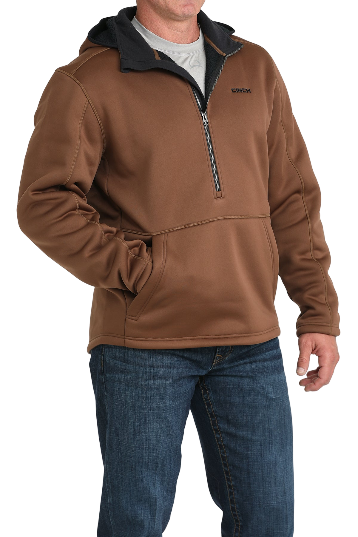 Man wearing a brown quarter-zip pullover with a black inner collar and a front kangaroo pocket, paired with blue jeans
