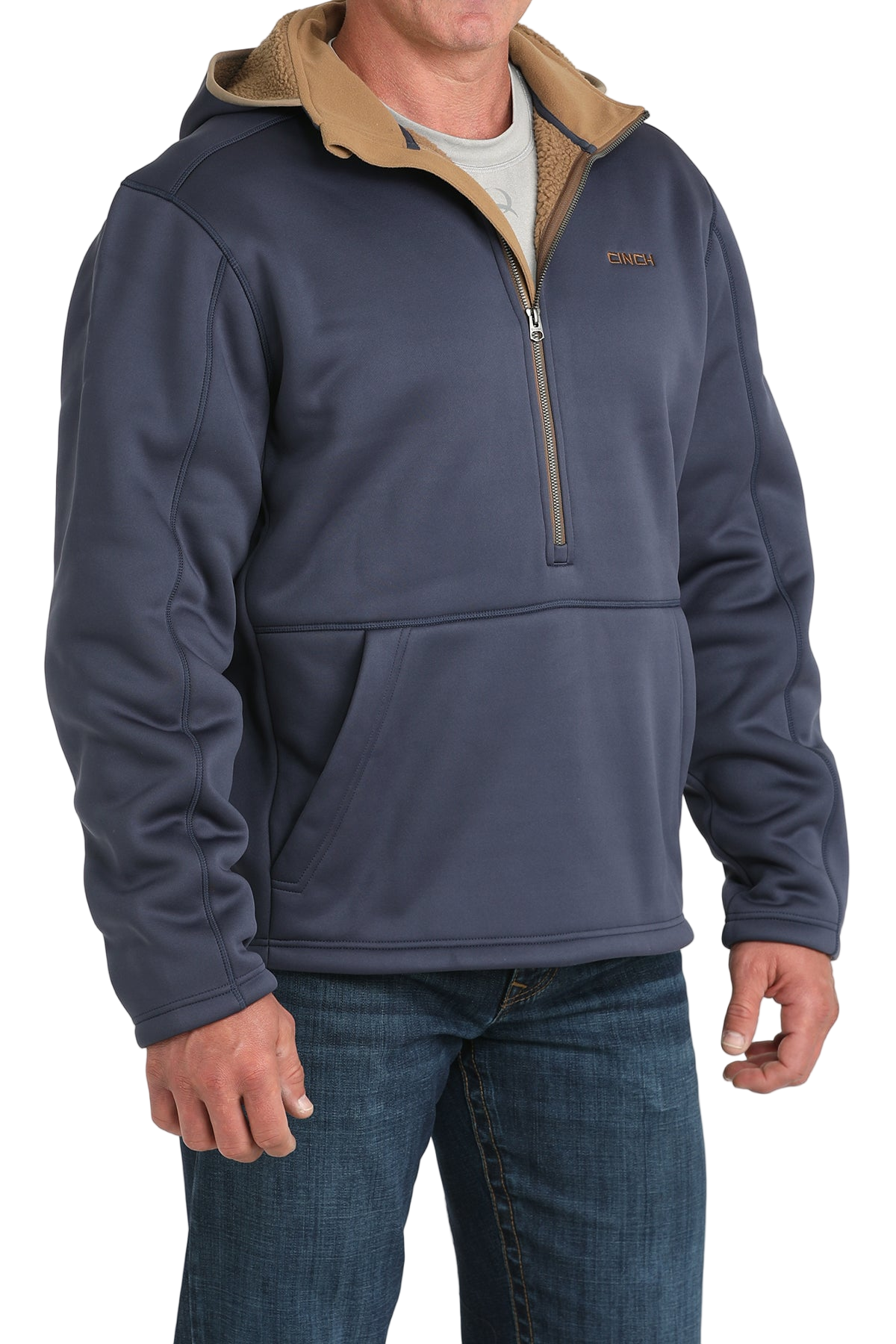 Man wearing a blue quarter-zip pullover with a tan inner collar and a front kangaroo pocket, paired with blue jeans