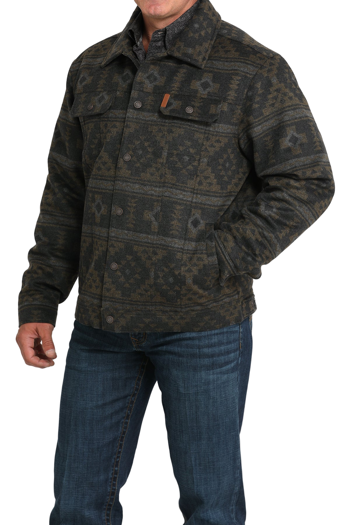 Man wearing a patterned dark green and black jacket with front buttons and chest pockets, paired with blue jeans