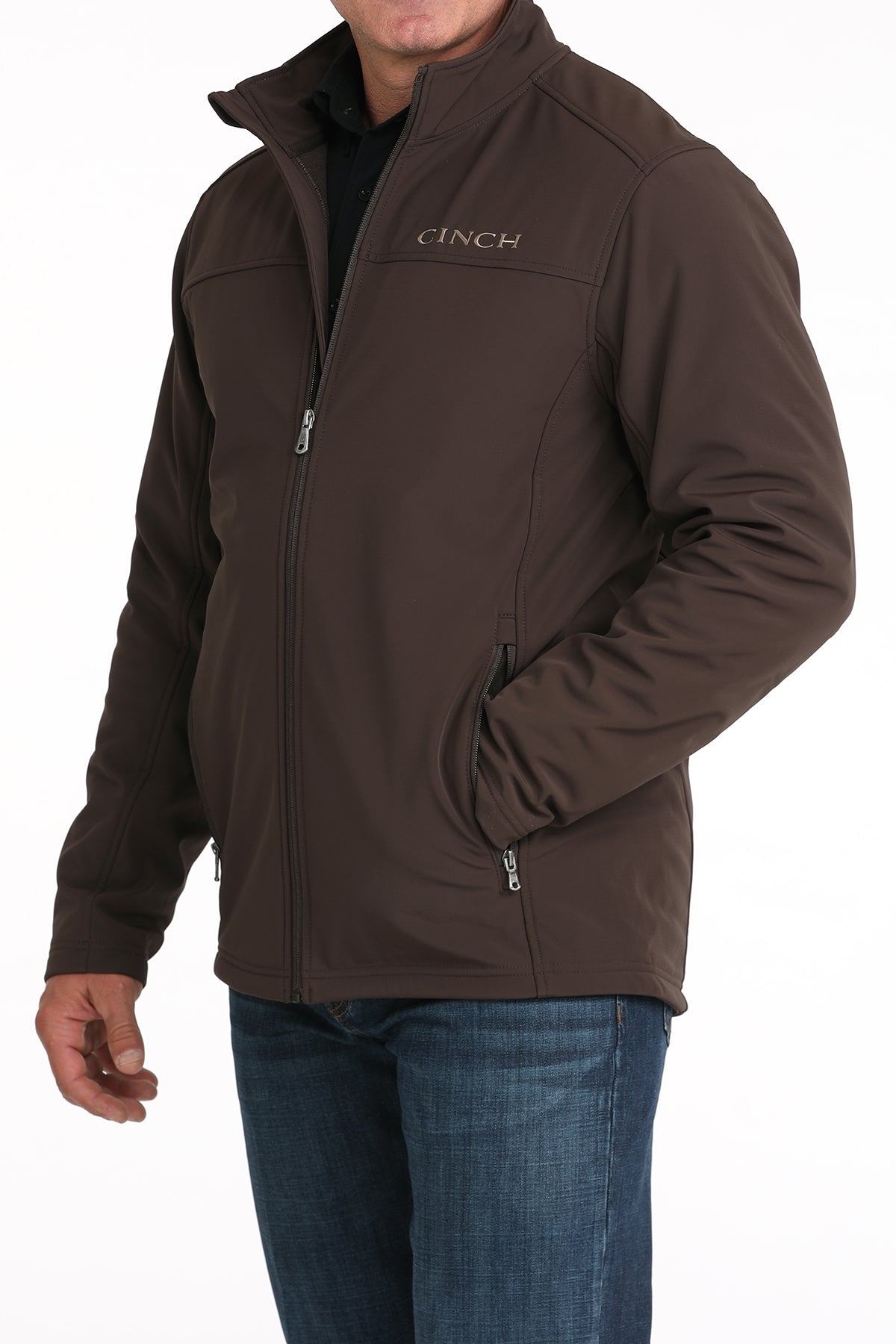 Man wearing a brown 'CINCH' jacket with jeans on a white background