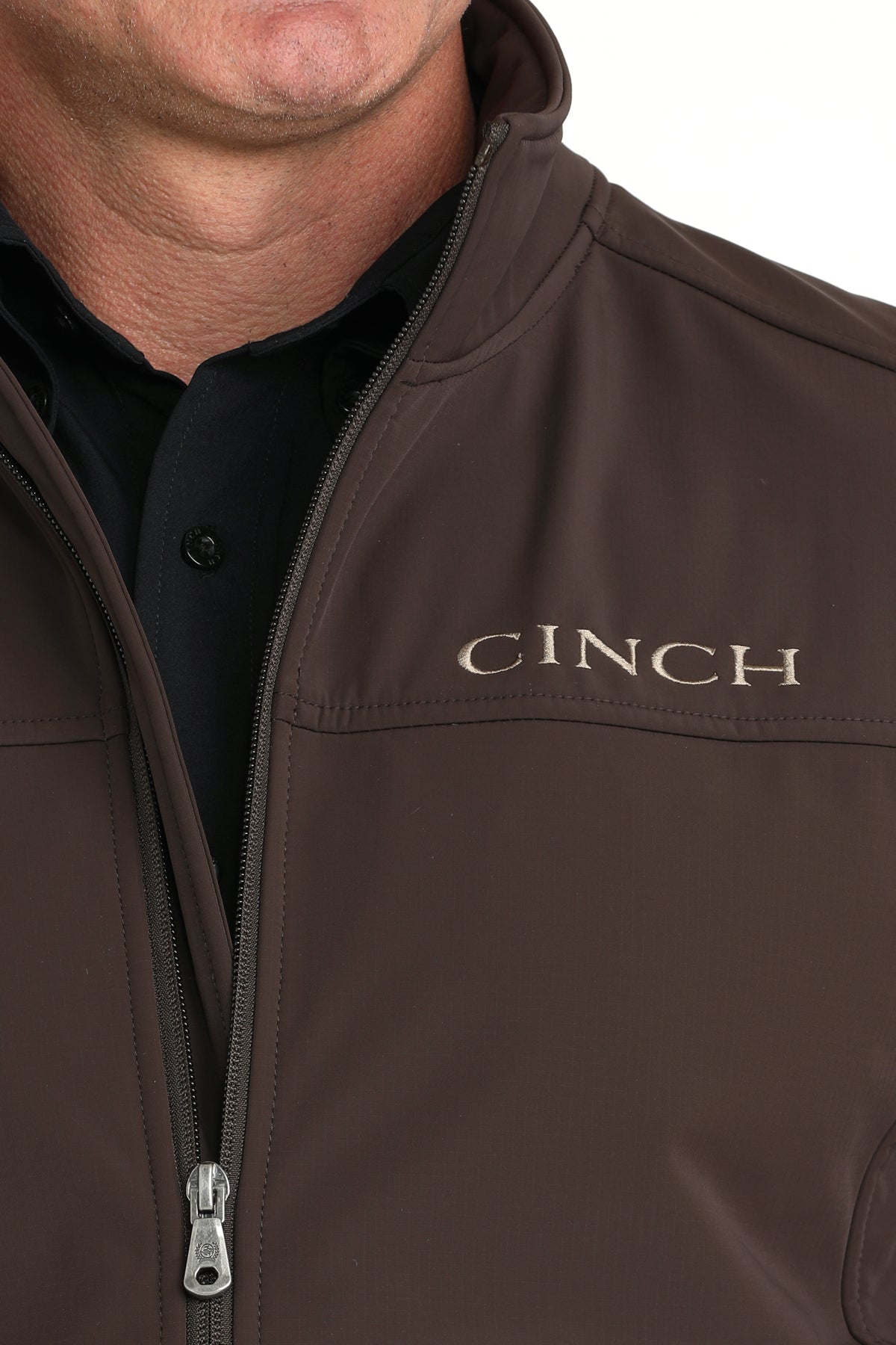 Close-up of a man wearing a brown 'CINCH' jacket on a white background