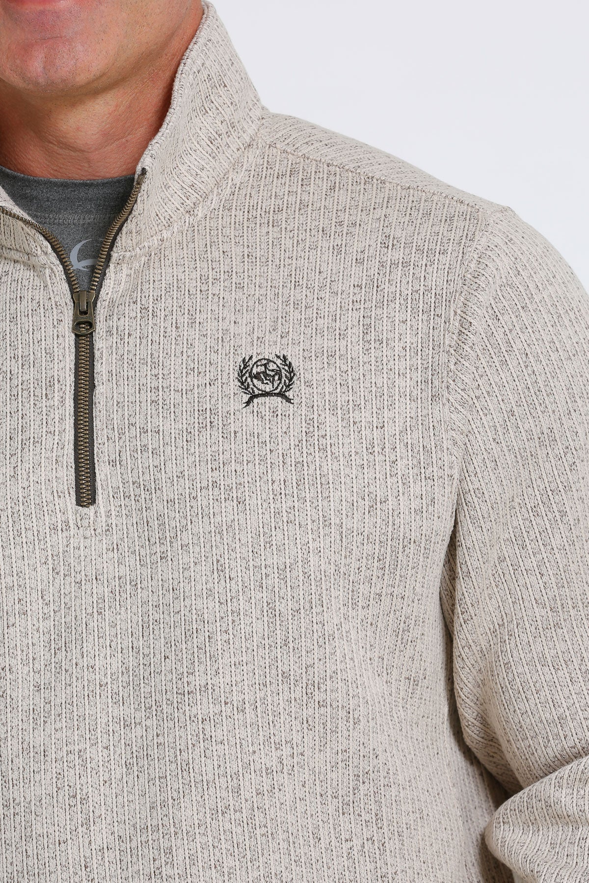 Close-up of a man wearing a khaki 1/4 zip sweater with a small 'CINCH' emblem