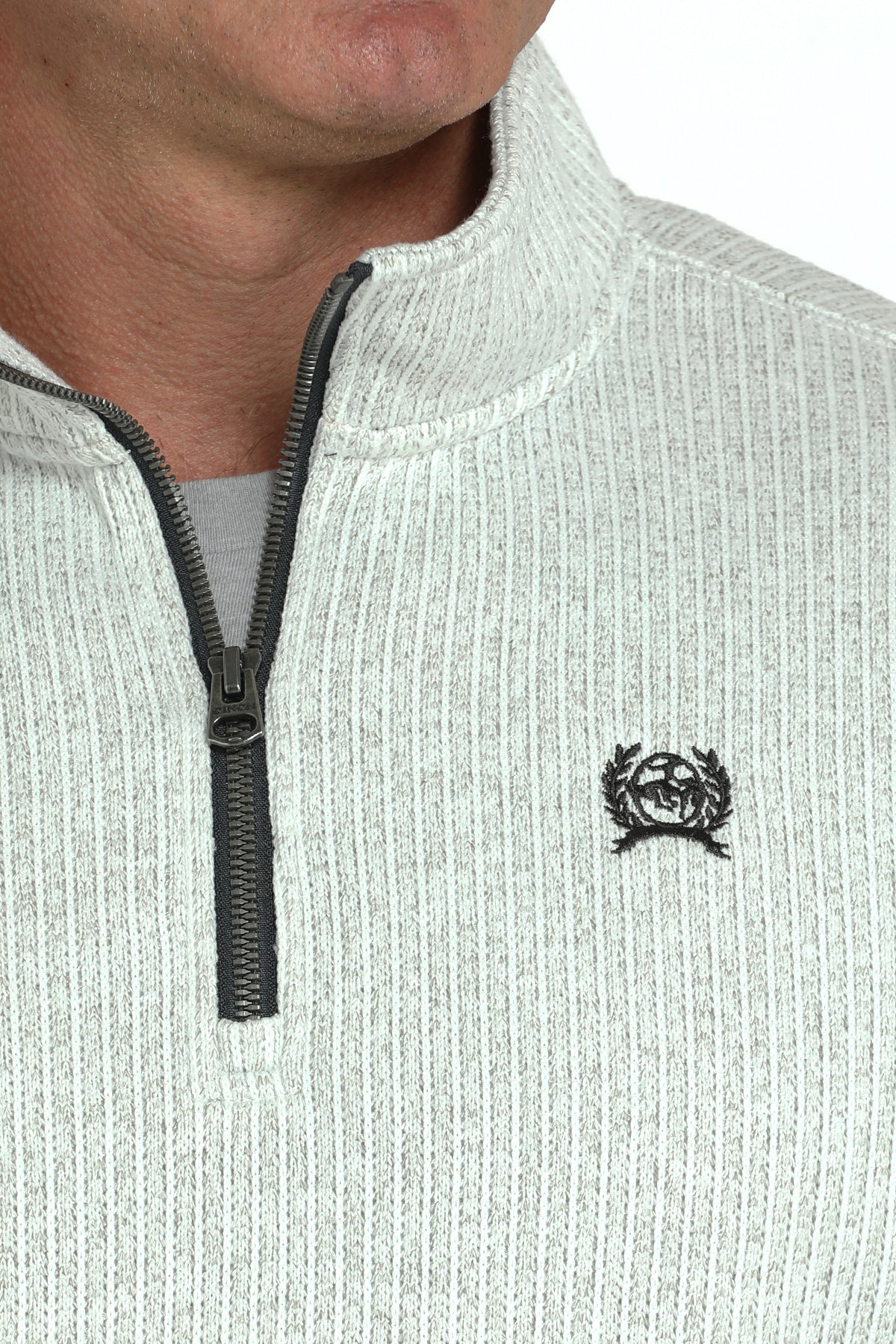 Close-up of a man wearing a light gray 1/4 zip jacket with a small 'CINCH' emblem