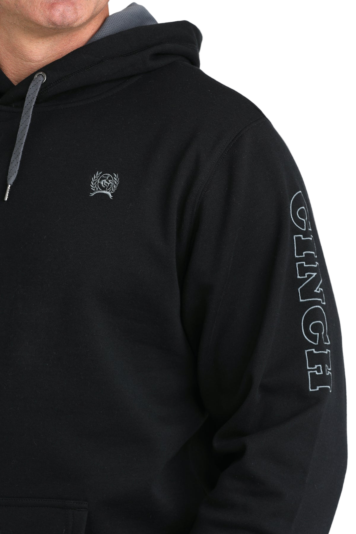 Close-up of a man wearing a black sweatshirt with a small logo on the chest and 'Cinch' written on the arm, displayed on a transparent background