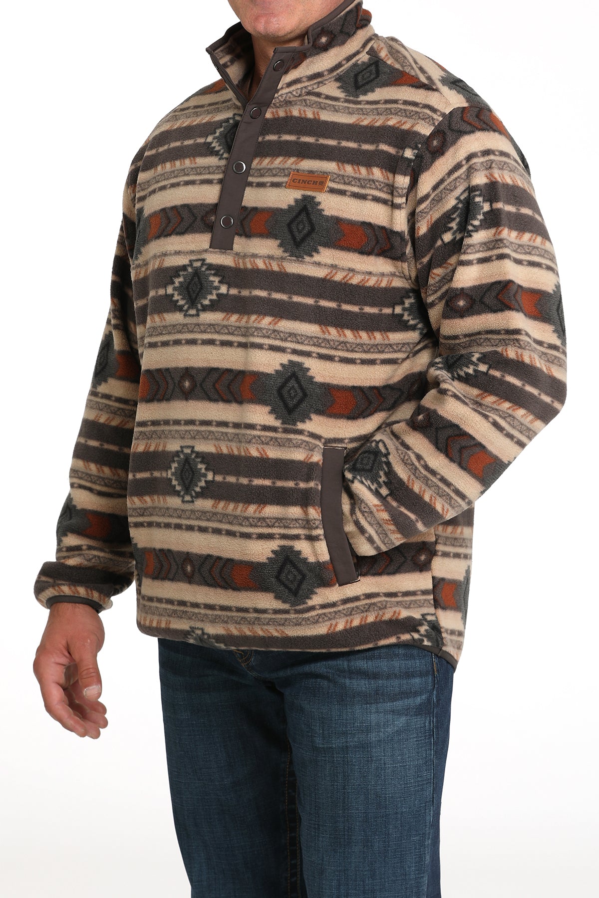 Man wearing a brown fleece pullover that has an all-over western pattern, paired with jeans
