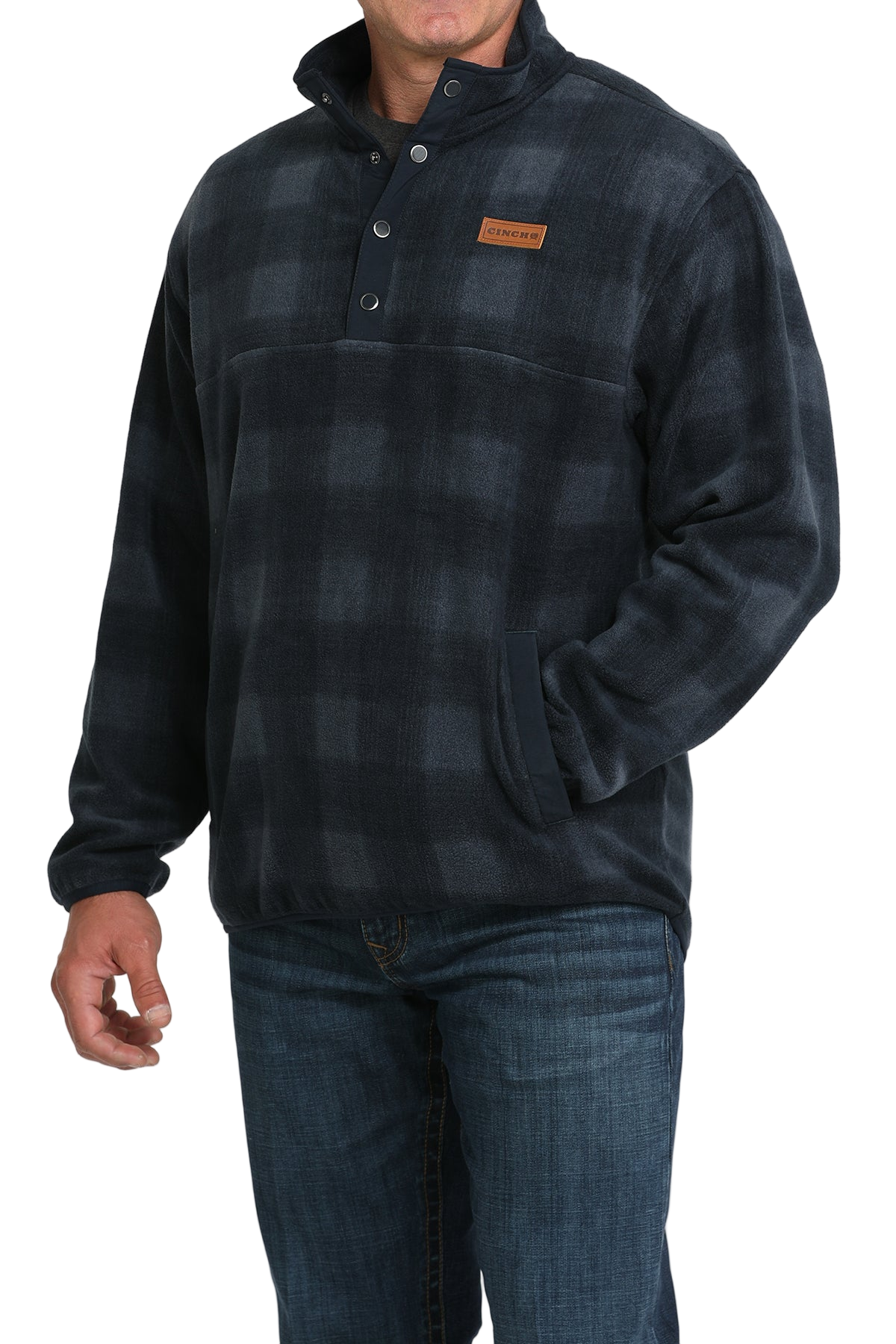 Man wearing a dark plaid fleece pullover with a buttoned collar and front pocket, paired with blue jeans