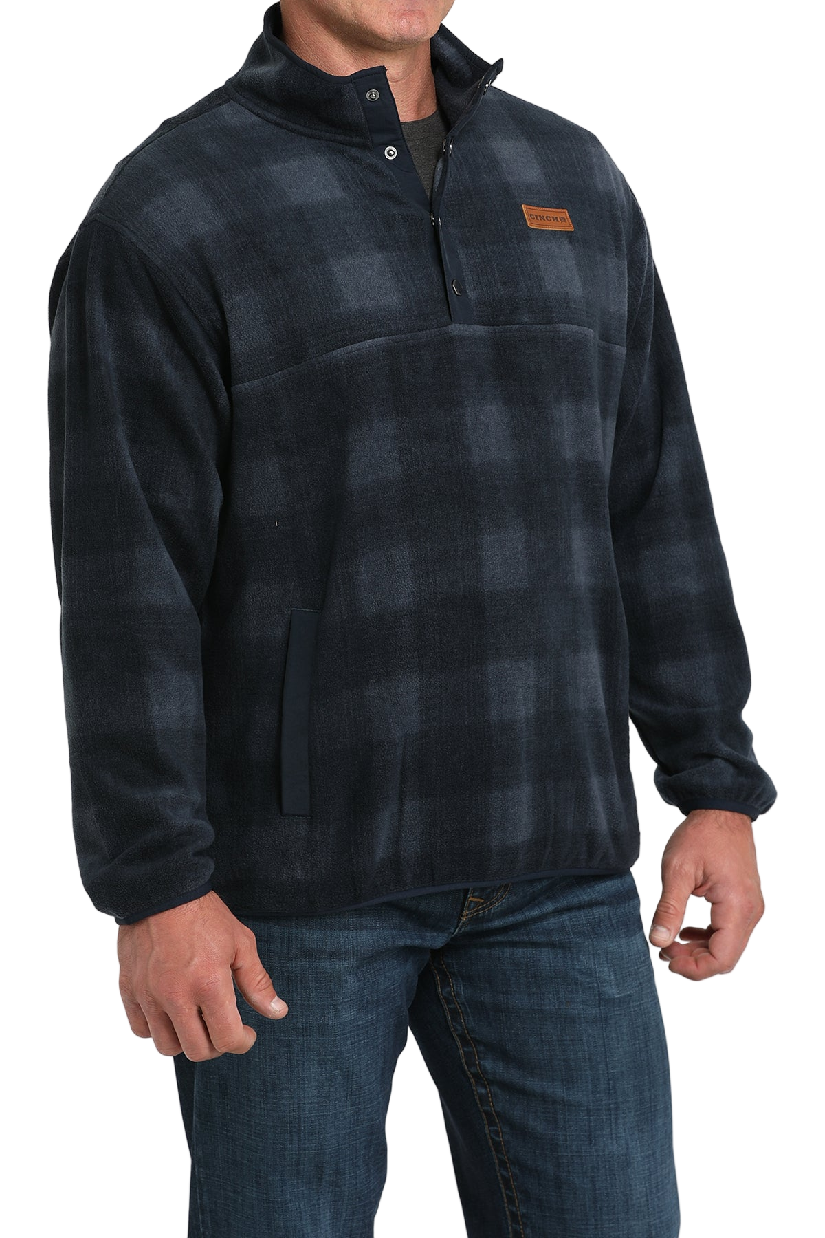 Man wearing a dark plaid fleece pullover with a buttoned collar and front pocket, paired with blue jeans
