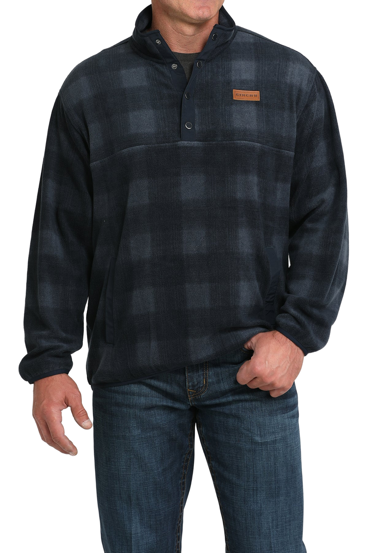 Man wearing a dark plaid fleece pullover with a buttoned collar and front pocket, paired with blue jeans