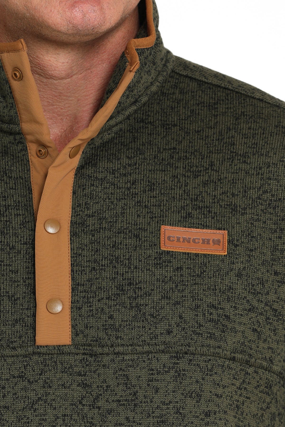 Close-up of a man wearing a green pullover jacket with buttons and a 'CINCH' logo