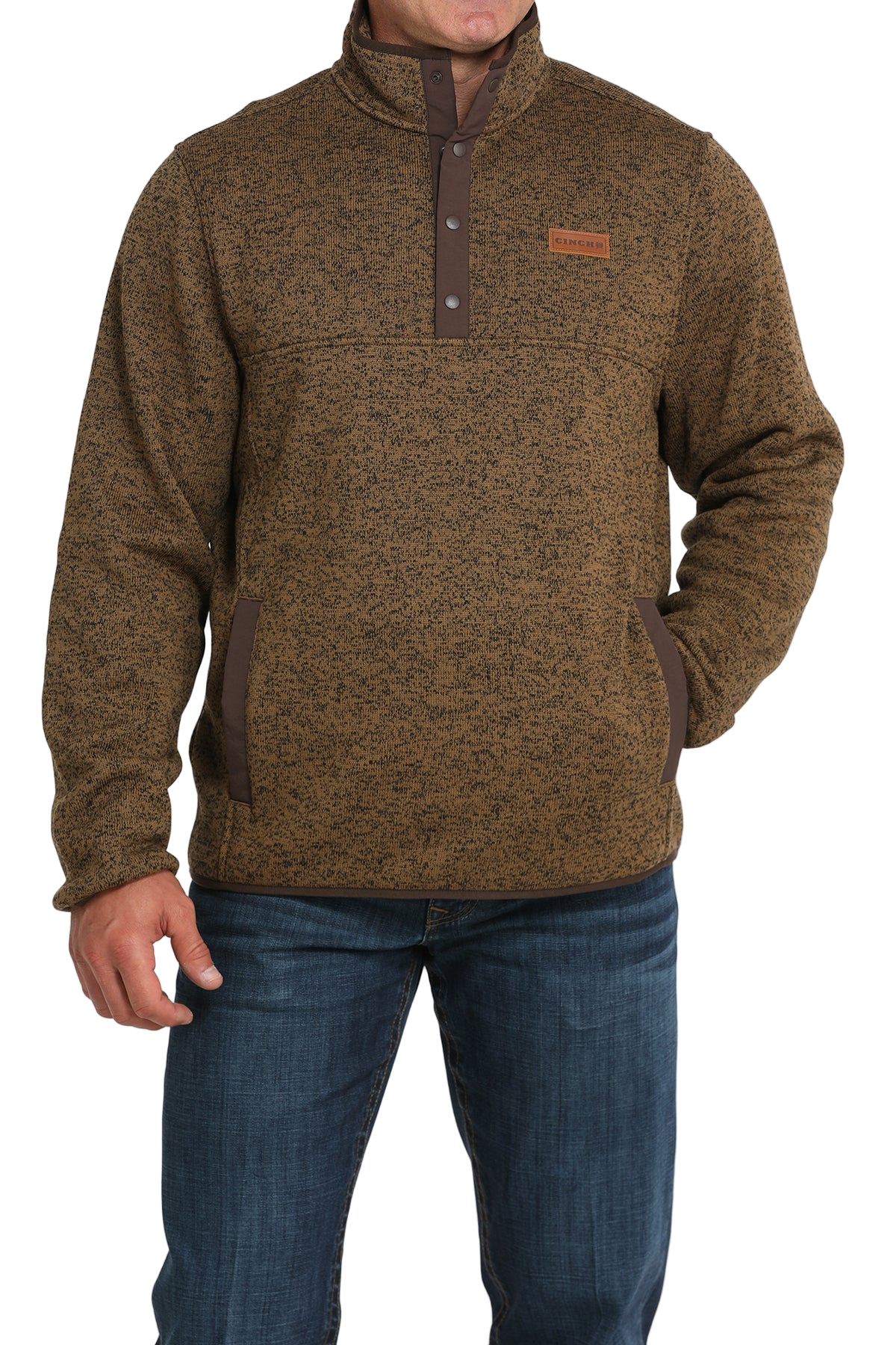 Man wearing a brown textured pullover with a snap-button placket, stand-up collar, and front hand pockets, paired with blue jeans