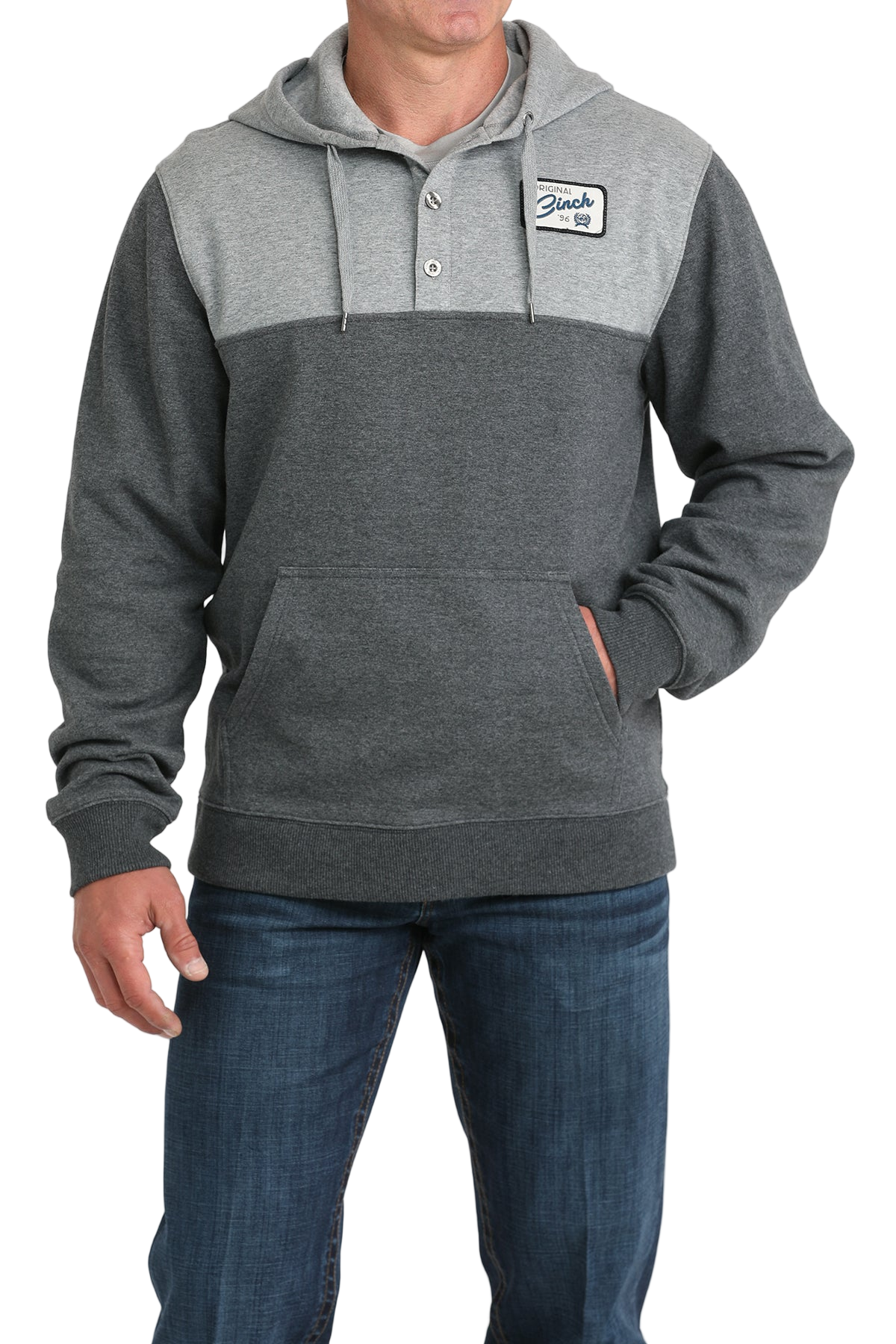 Man wearing a two-tone gray hoodie with a buttoned placket, drawstring hood, a small chest patch, and a front kangaroo pocket, paired with blue jeans
