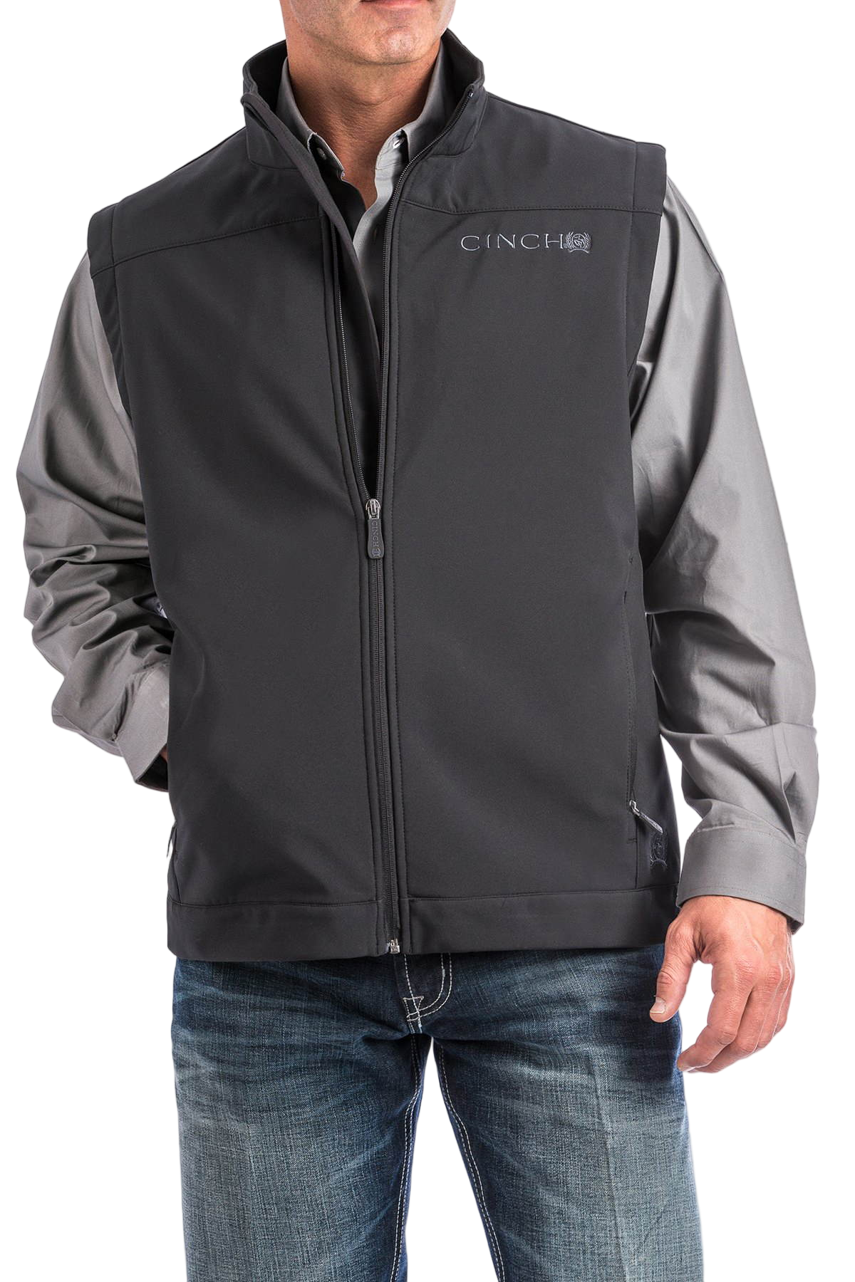 Man wearing a black CINCH vest over a gray button-down shirt, paired with blue jeans