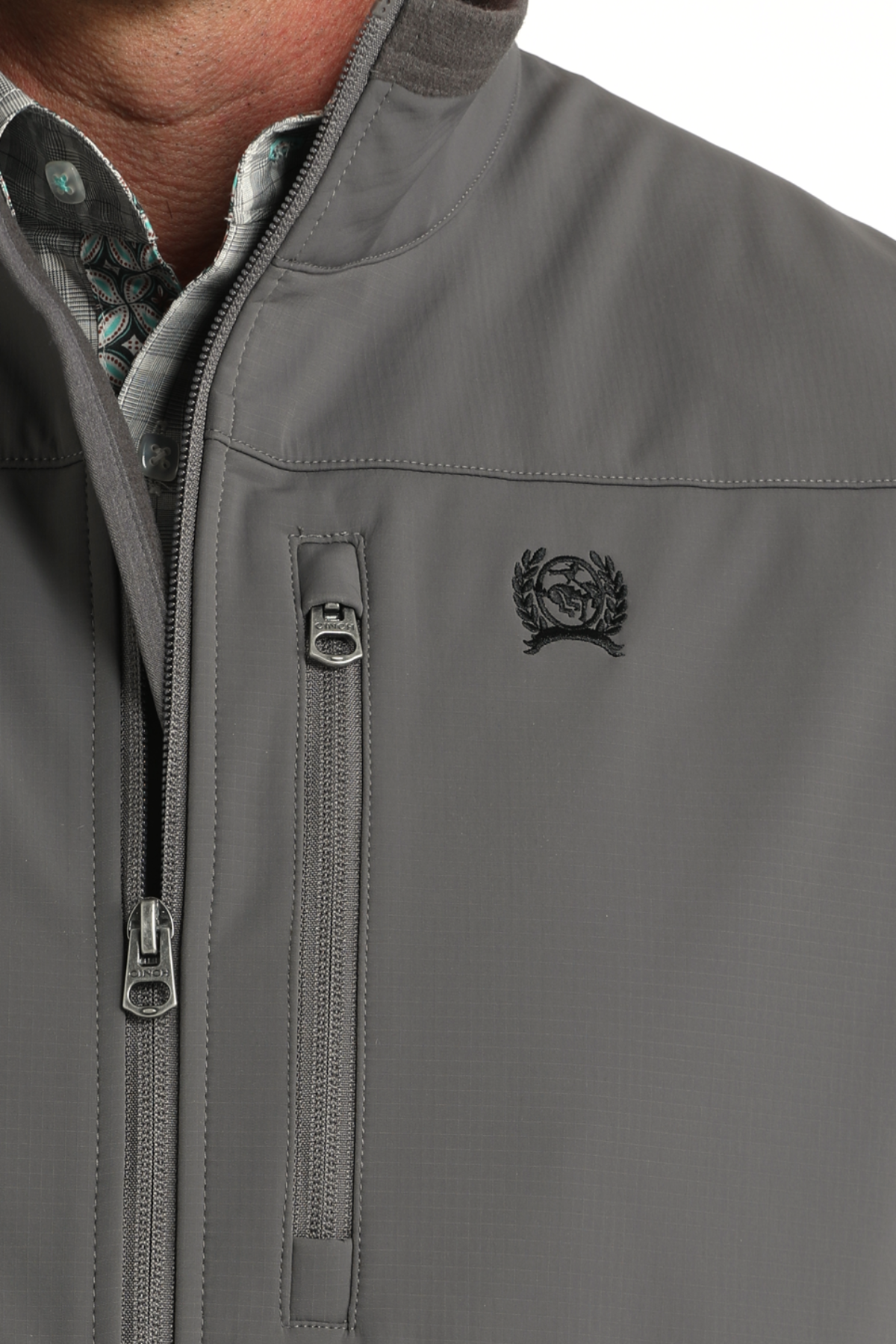 Gray jacket with a brand logo on the chest, close-up view.