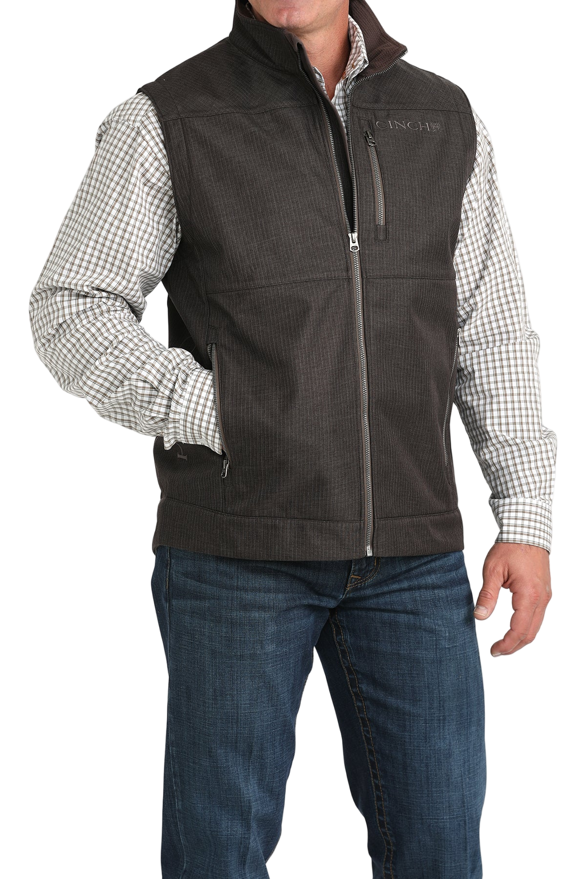 Man wearing a dark brown textured vest over a checked long-sleeve shirt, paired with blue jeans