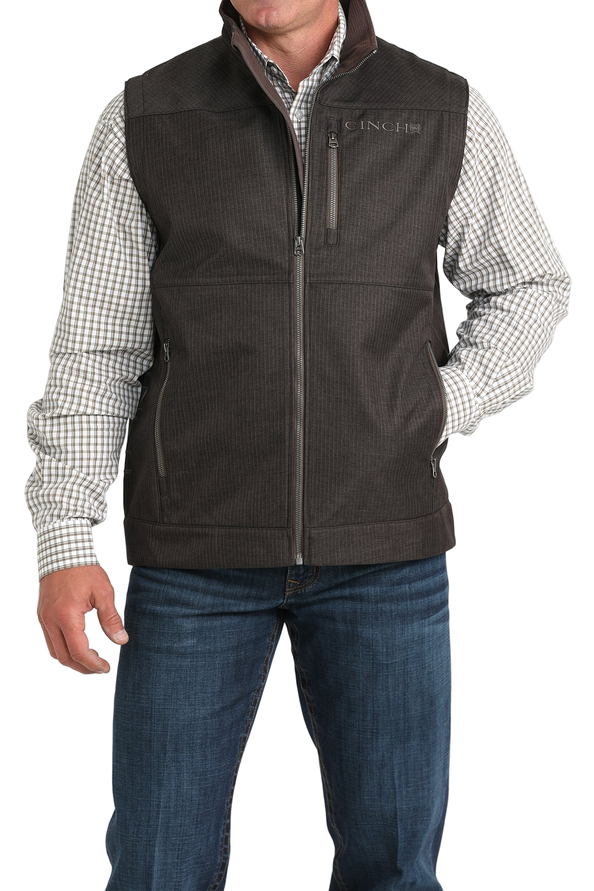 Man wearing a dark brown textured vest over a checked long-sleeve shirt, paired with blue jeans