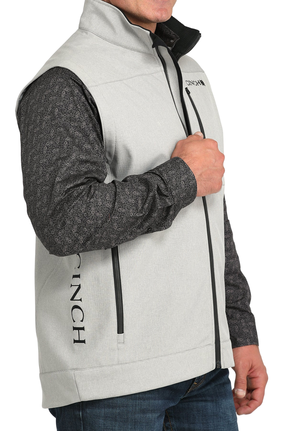 Man wearing a light gray zip-up vest over a gray long-sleeve shirt and jeans