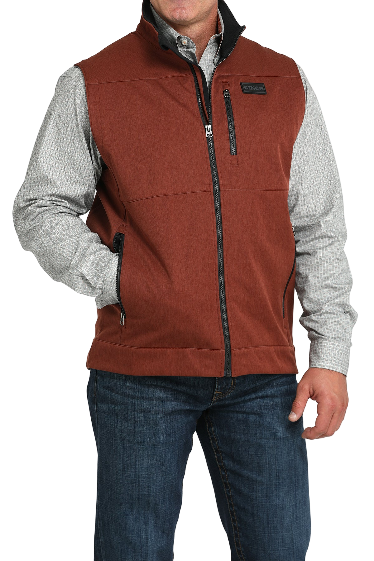 Man wearing a rust orange zip-up vest over a white long-sleeve shirt and jeans