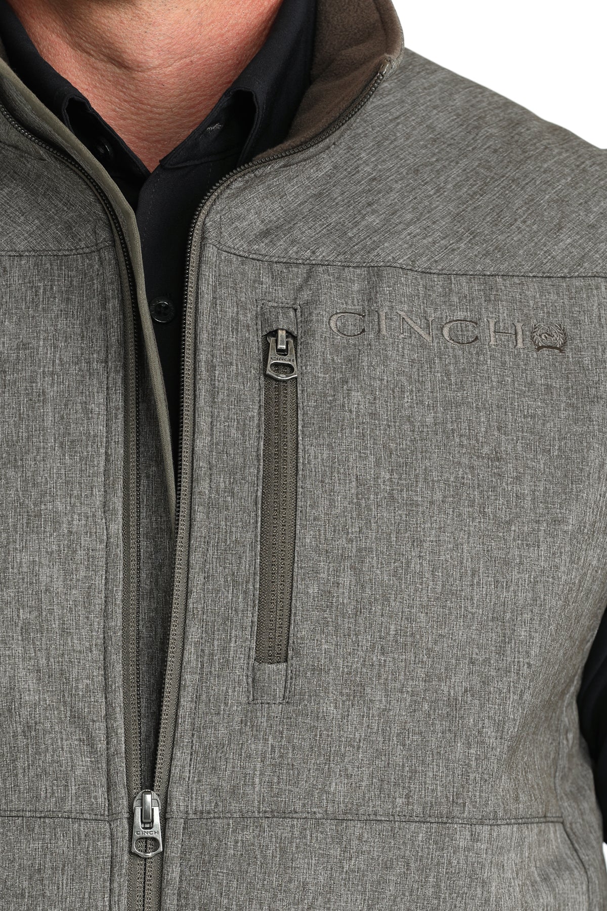 Close-up of a an wearing a green vest with zip-up pocket on the chest and a 'CINCH' logo