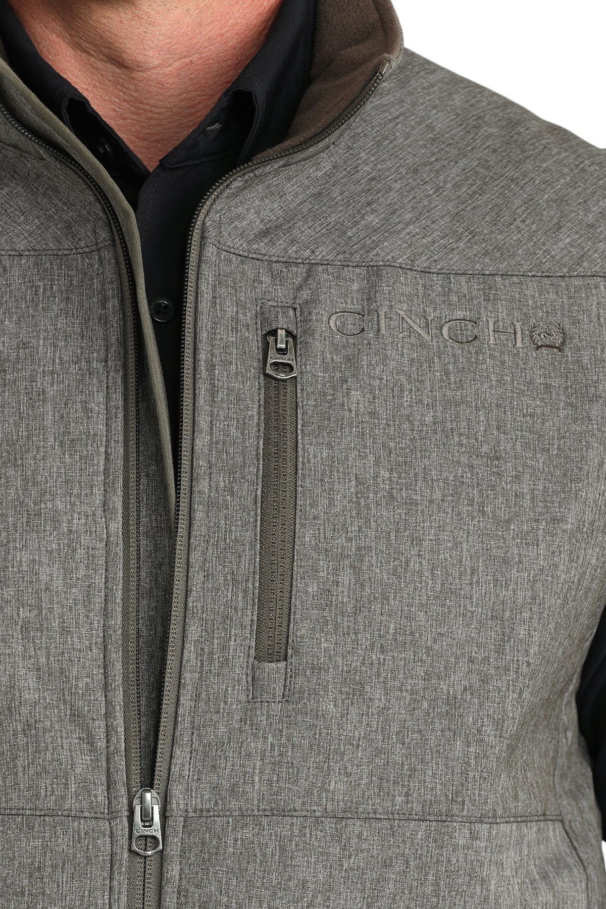 Close-up of a man wearing a gray zip-up vest over a black shirt