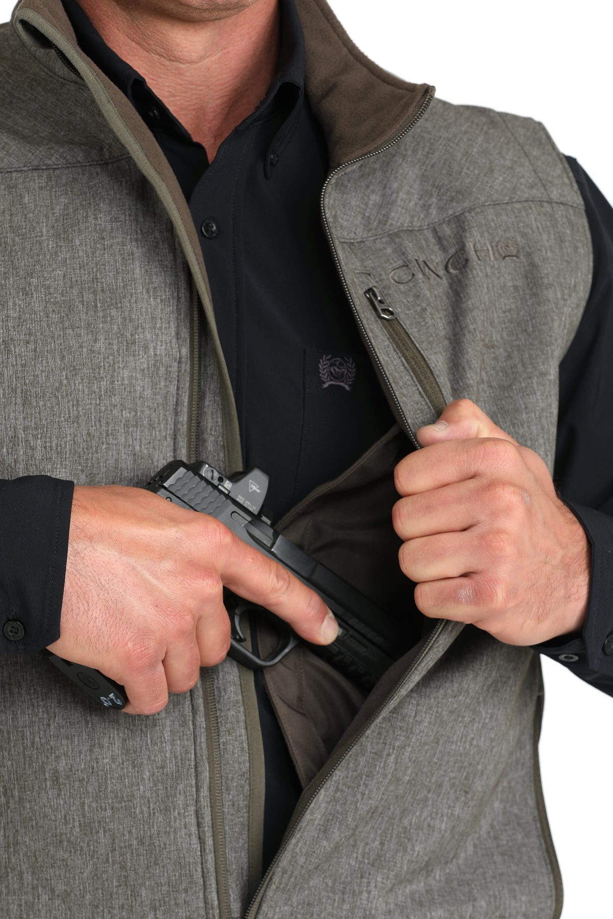 Man wearing a gray vest with a long sleeve button-down undershirt, partially showing a firearm going into the concealed carry pocket