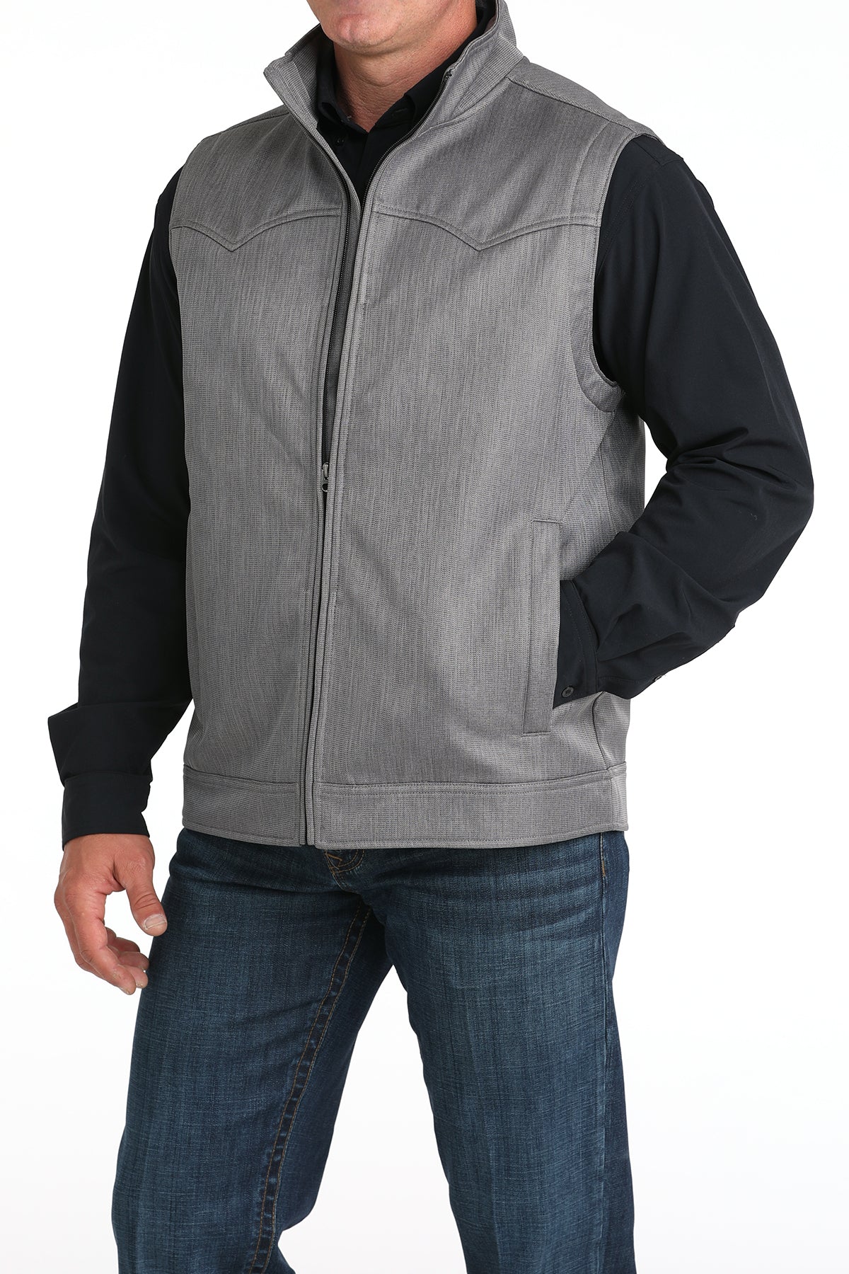 Man wearing a gray vest with a back undershirt and jeans