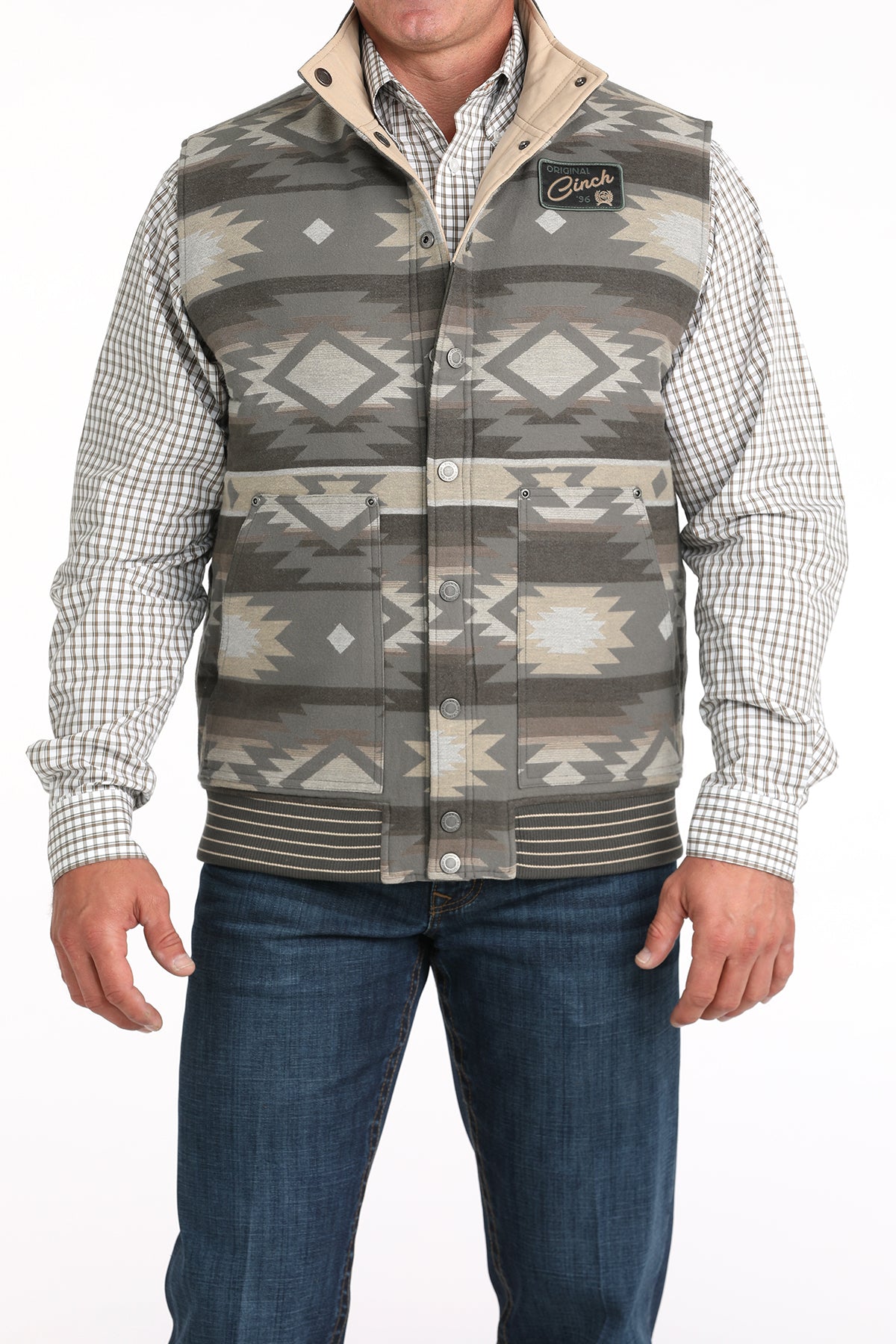 Man wearing a vest with a western pattern with an undershirt and jeans