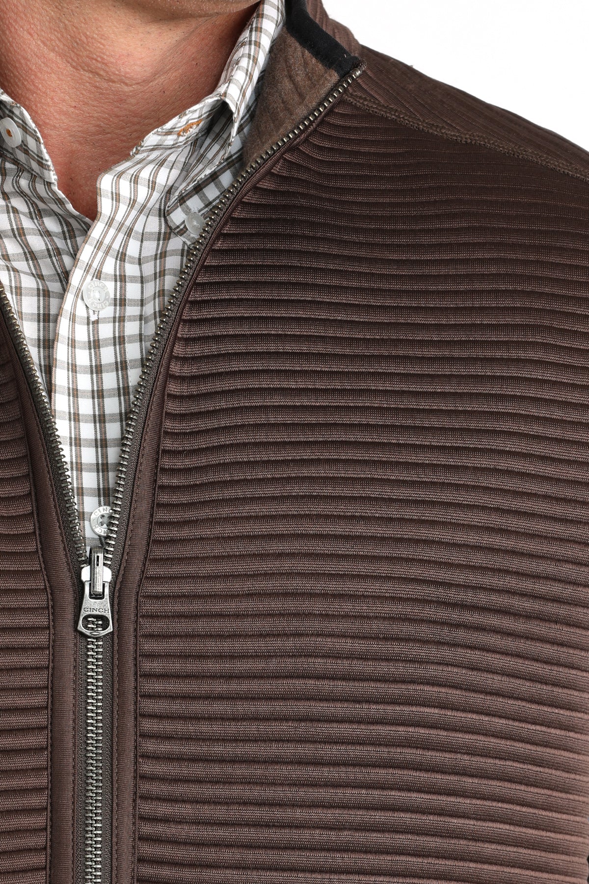 Close-up of a man wearing a brown vest with a checkered long sleeve undershirt