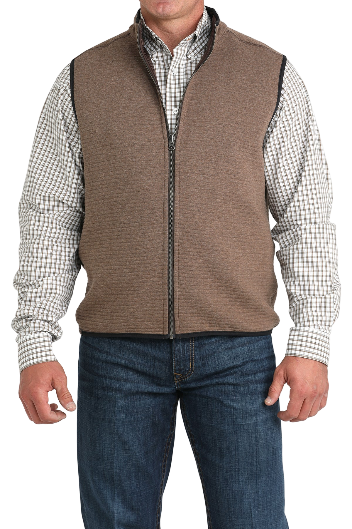 A man wearing a brown zip-up vest over a white and brown checkered button-down shirt, paired with blue jeans