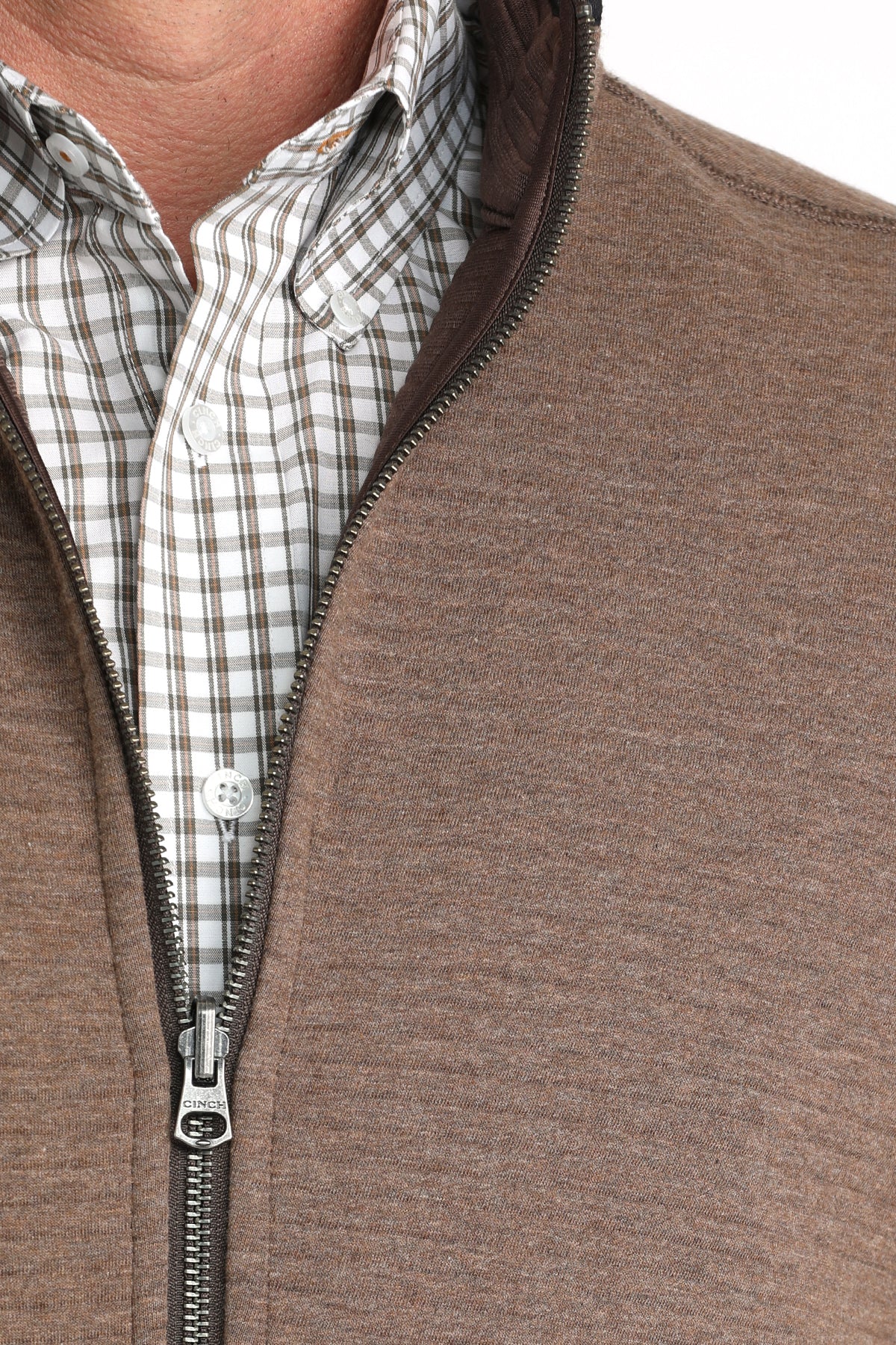 Close-up of a man wearing a brown vest with a checkered long sleeve undershirt